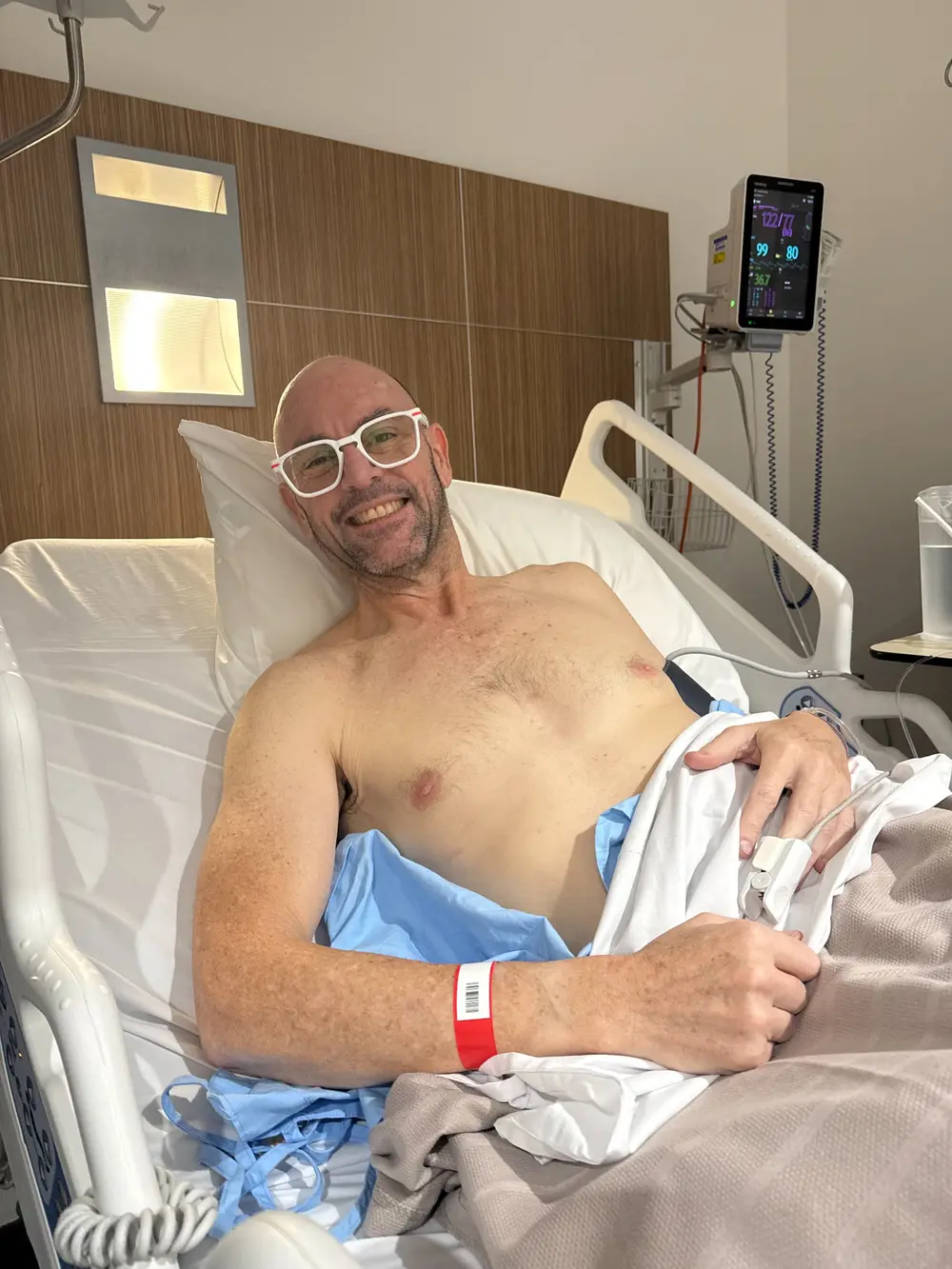 Adam smiling in a hospital bed after hamstring surgery